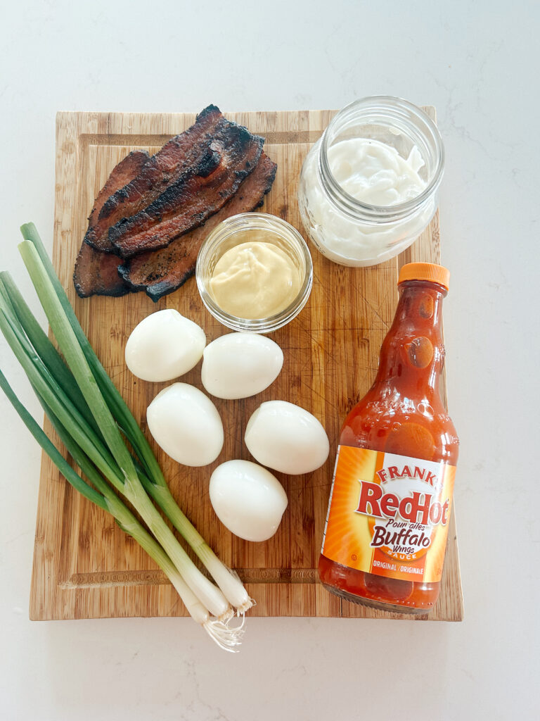 bacon, eggs, green onions and sauces on a wood board