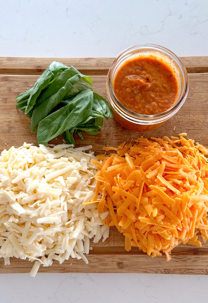 Tomato sauce, grated cheese and fresh basil on a wood board