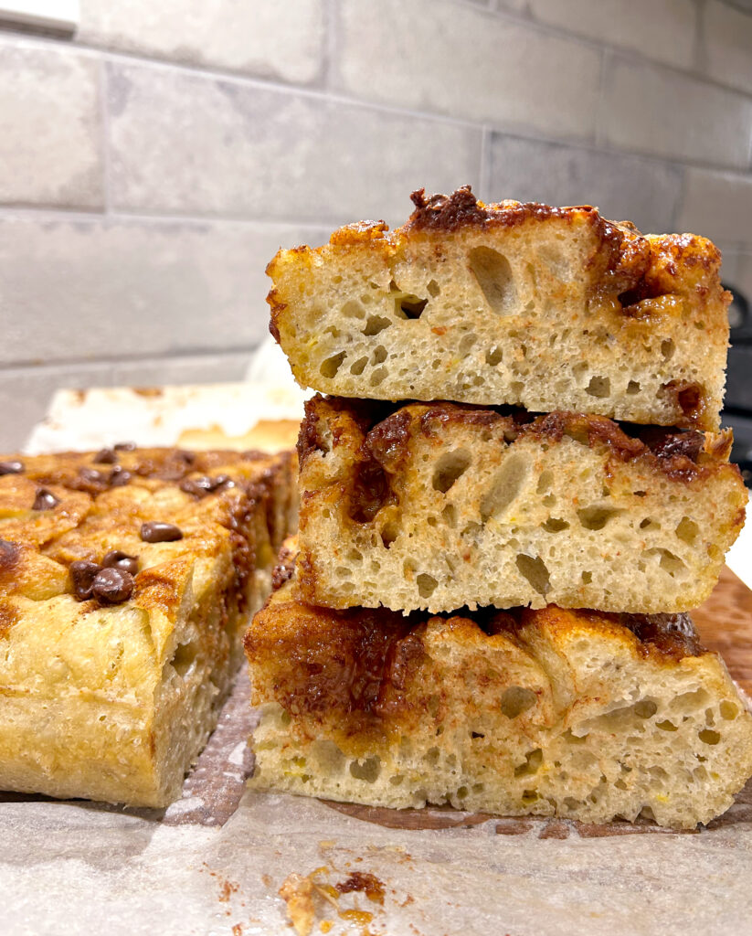 focaccia bread stacked in front of a grey brick backsplash