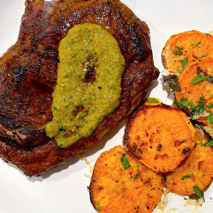 steak with sweet potatoes and chimichurri on a white plate