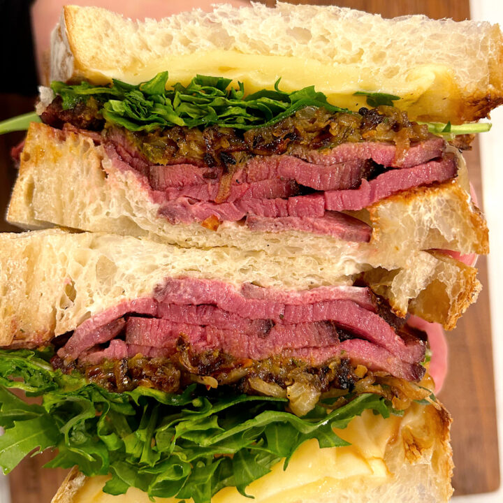 inside of a steak sandwich with arugula and onions