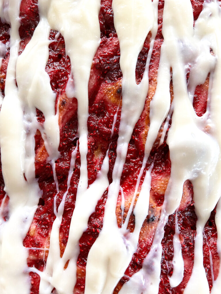 close up of focaccia bread with raspberries and cream cheese icing