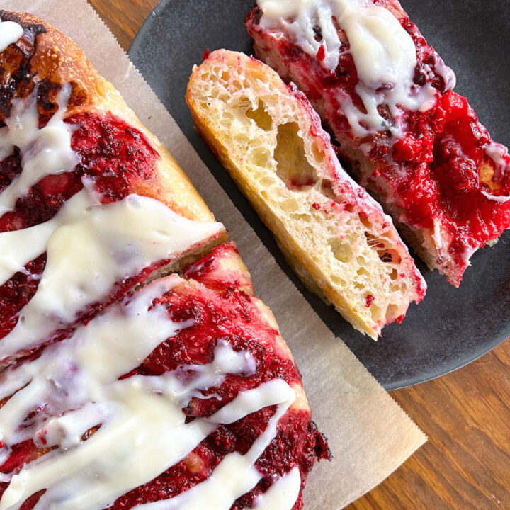 sliced focaccia bread with raspberries and cream cheese icing