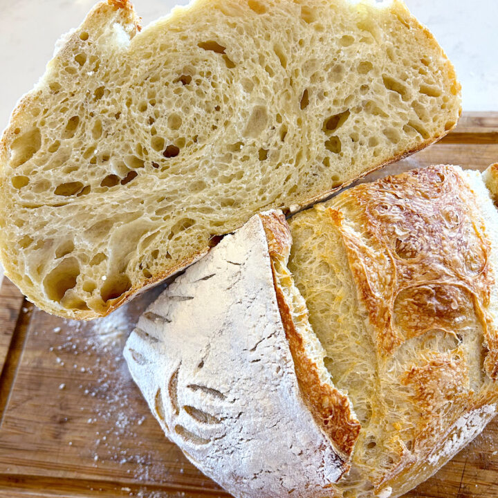 loaf of fresh bread cut in half on a wood board