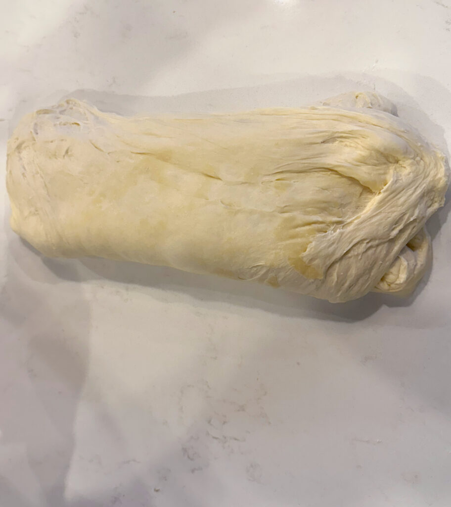 dough being folded on a white counter