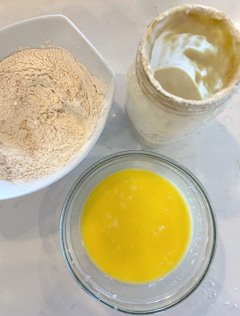 butter, flour and sourdough starter on a white counter