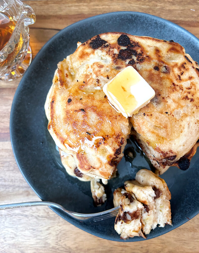 pancakes with butter and syrup on a dark grey plate