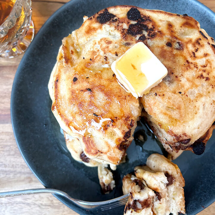 pancakes with butter and syrup on a dark grey plate