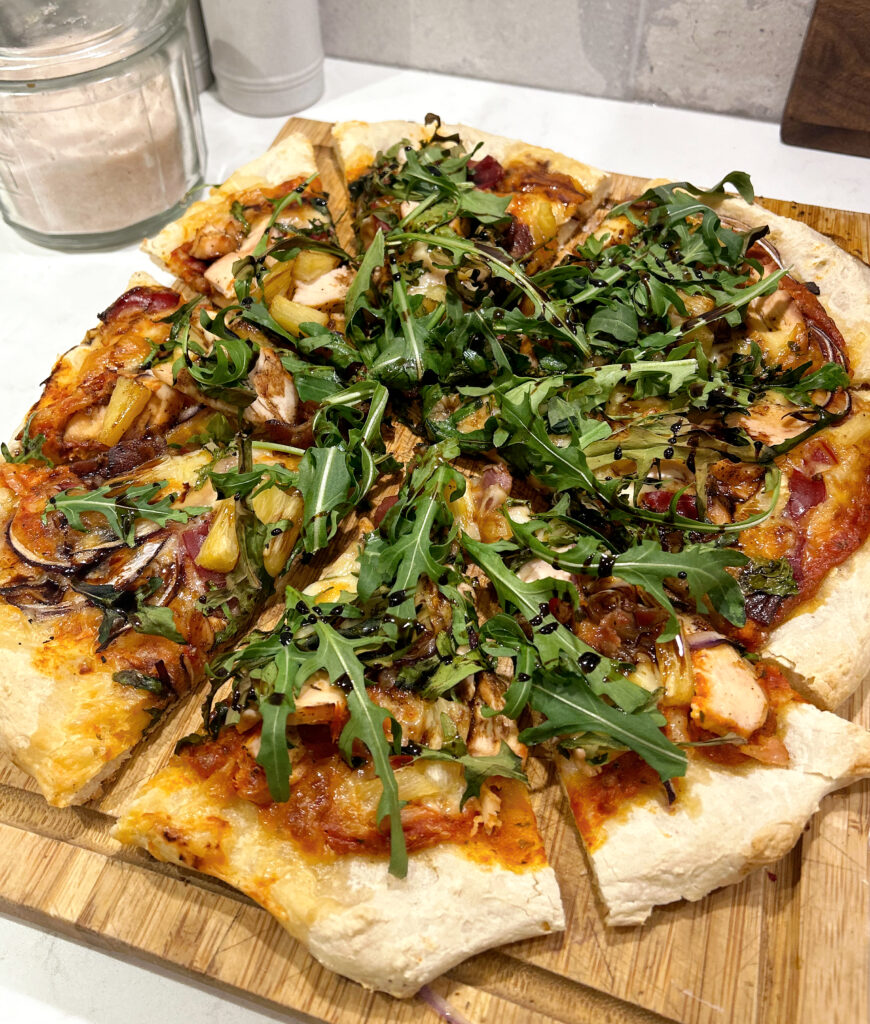 pizza with tomato sauce and arugula on a wood board