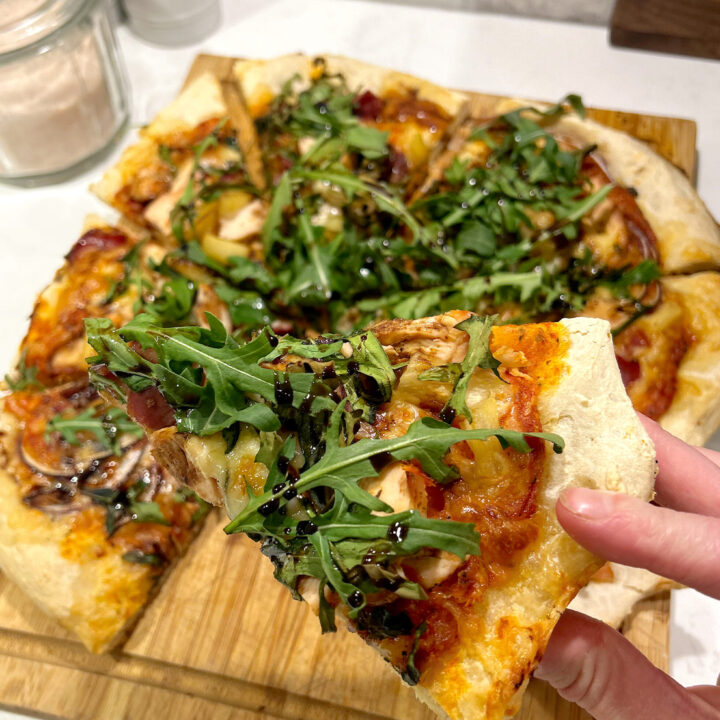 pizza with arugula and tomato sauce on a wood board