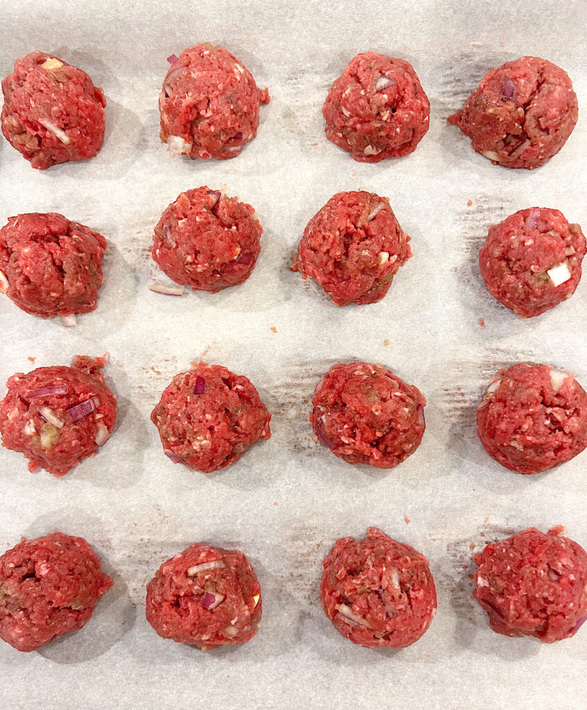 unbaked meatballs on a baking sheet
