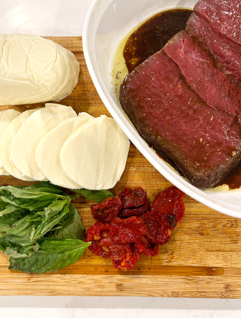 mozzarella, basil, tomatoes and red meat on a wood boars
