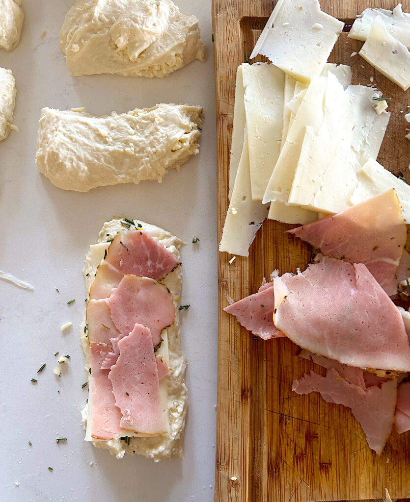 bread rolls being filled with ham and cheese