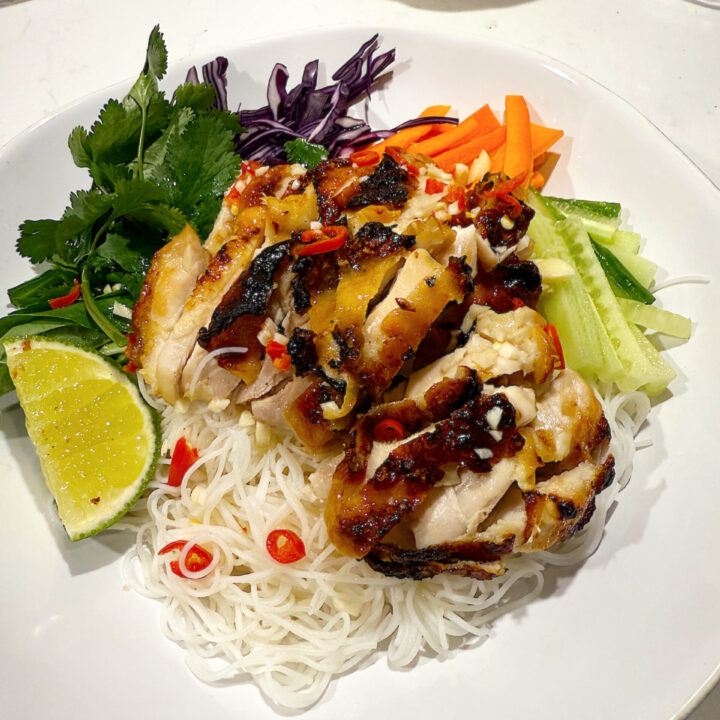 rice noodles with chicken and vegetables in a white bowl