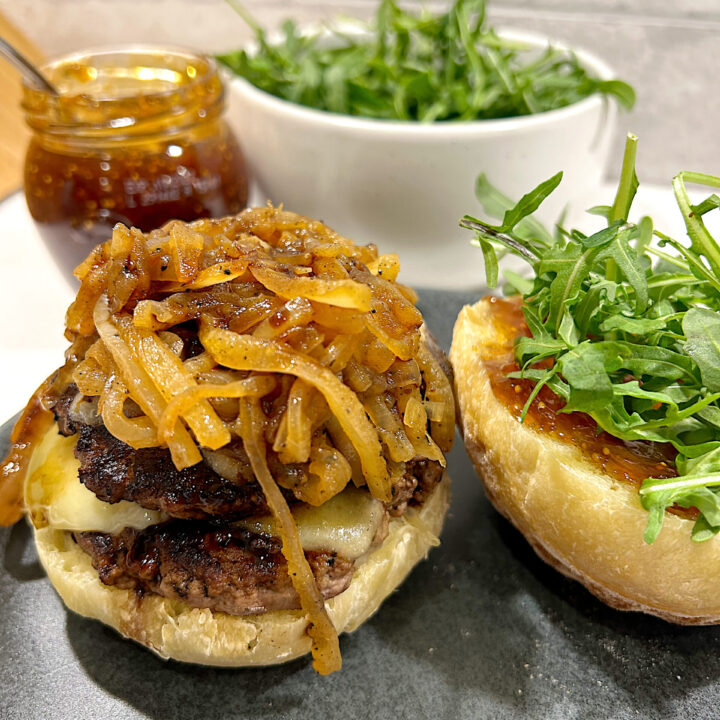 burger with caramelized onions, gruyere cheese and arugula on a sourdough bun
