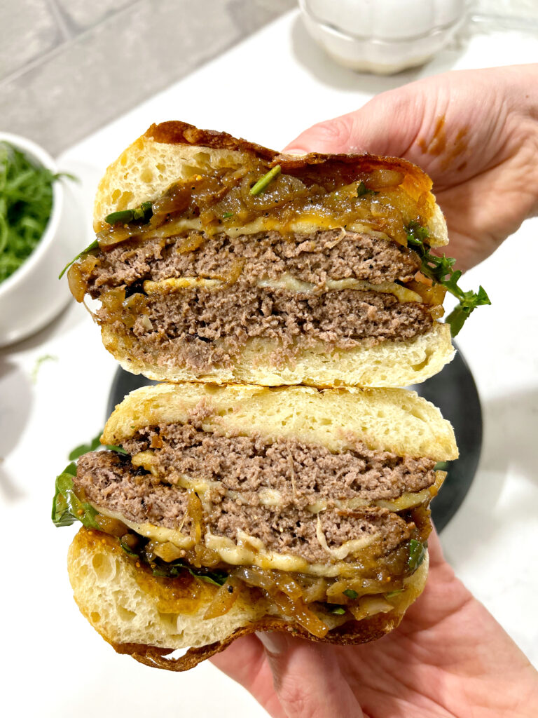 burger cut in half with caramelized onions and gruyere cheese on a sourdough bun