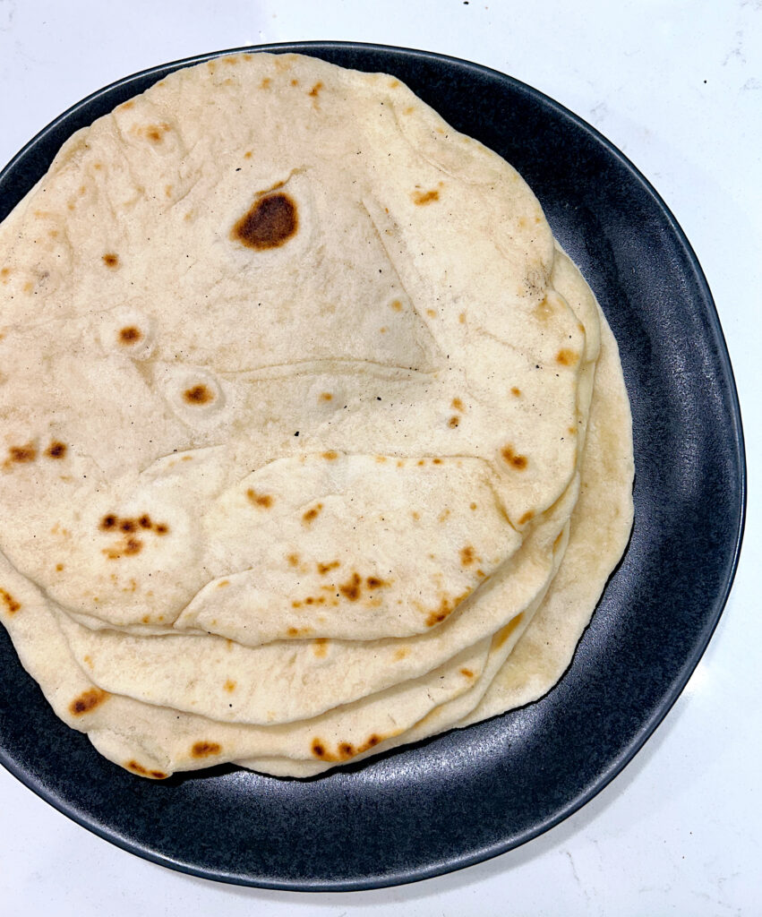 stack of fresh tortillas on a dark grey plate