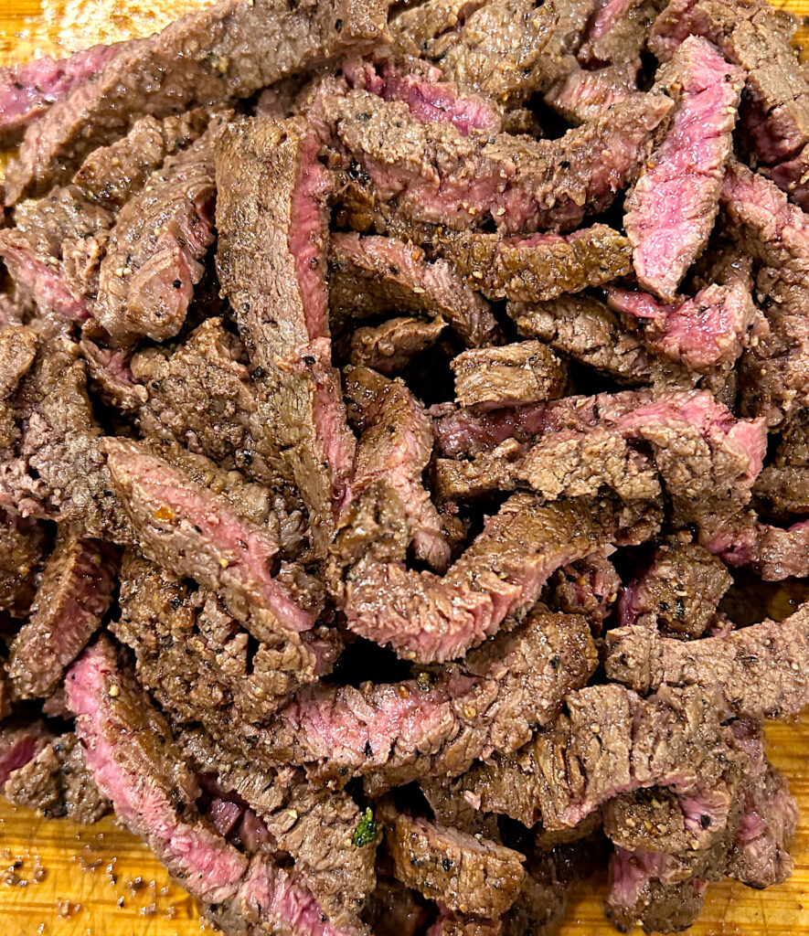 sliced medium rare steak on a cutting board