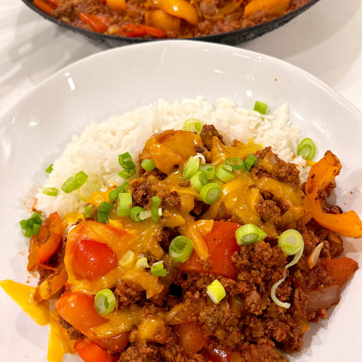 ground meat with tomatoes and pepper over rice in a white bowl