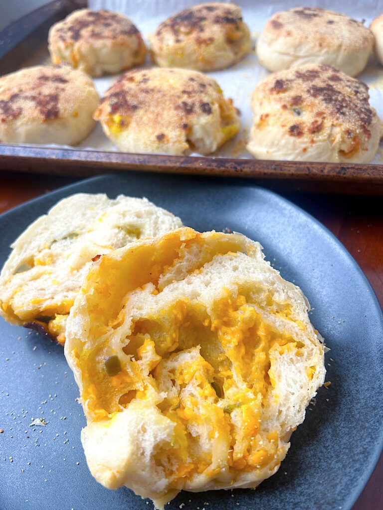 cheesy english muffins cutin half on a black plate