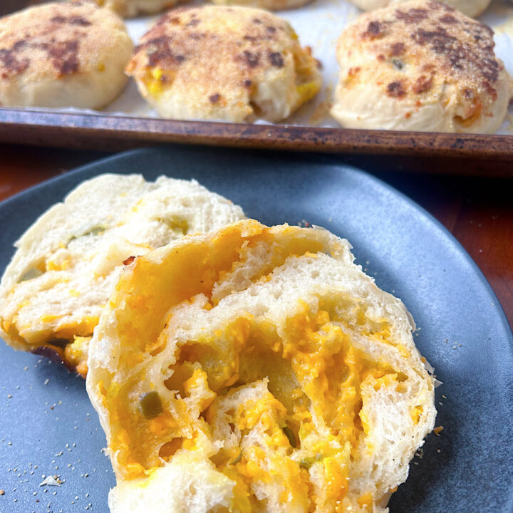cheesy english muffins cutin half on a black plate