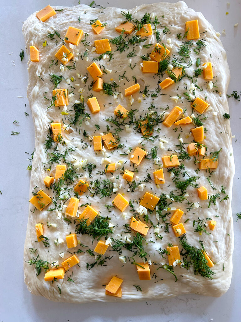 bread dough on a counter with chese and dill on top