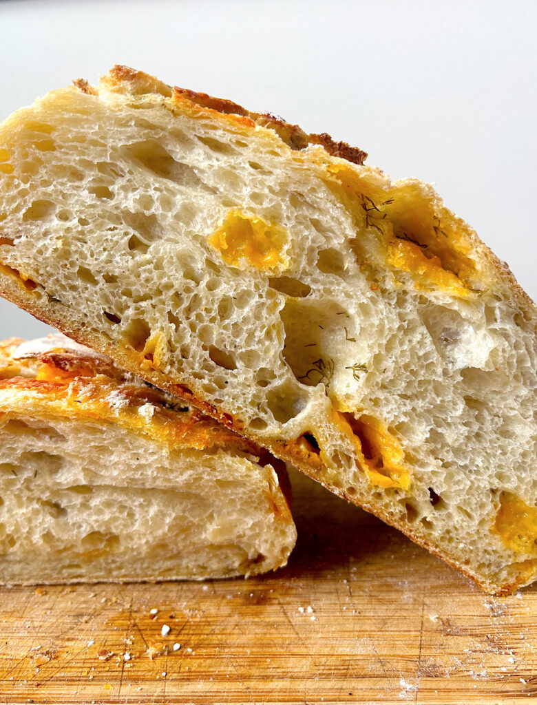 loaf of cheesy bread cut in half on a wood board