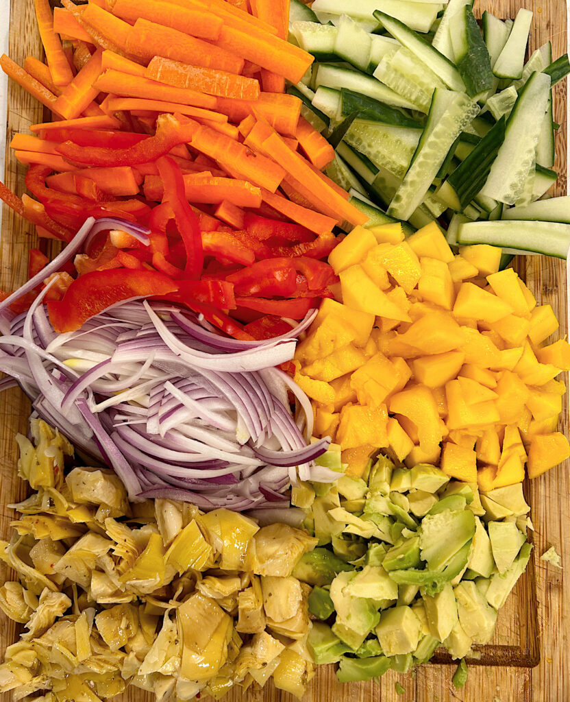 chopped mango, avocado and vegetables on a wood board