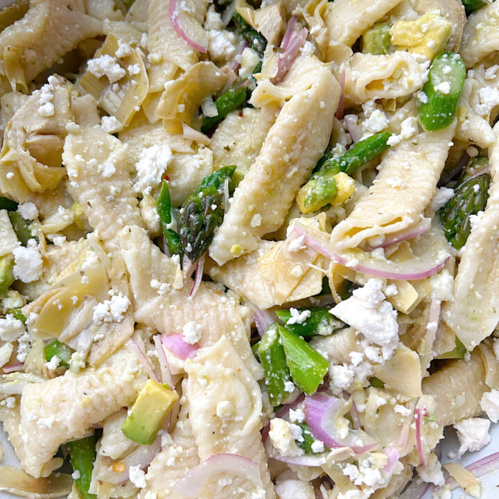 pasta in a bowl with asparagus, avocado, red onion and feta cheese
