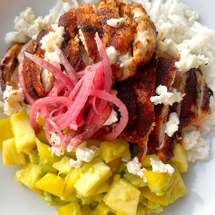 white bowl with rice, chicken,pineapple and picked red onions