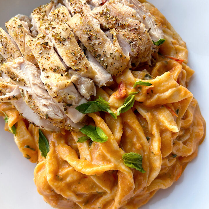 fresh bowl of pasta with red suace and chicken thighs on top
