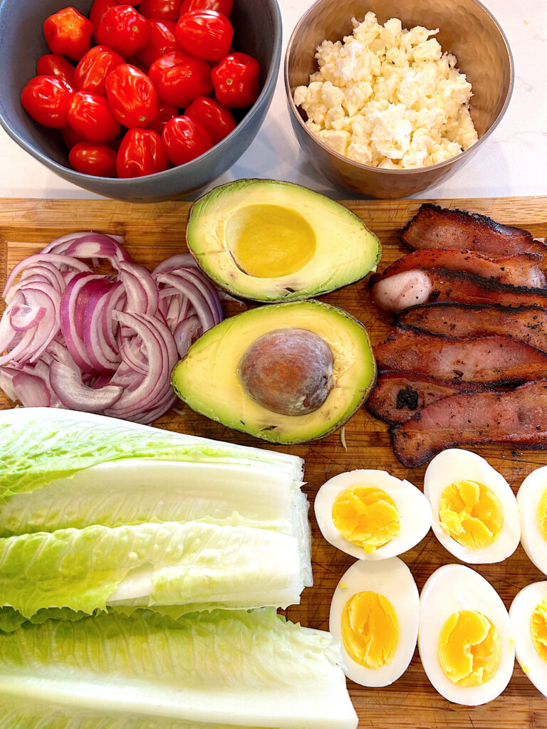 lettuce, avocado, bacon and eggs on a wood board