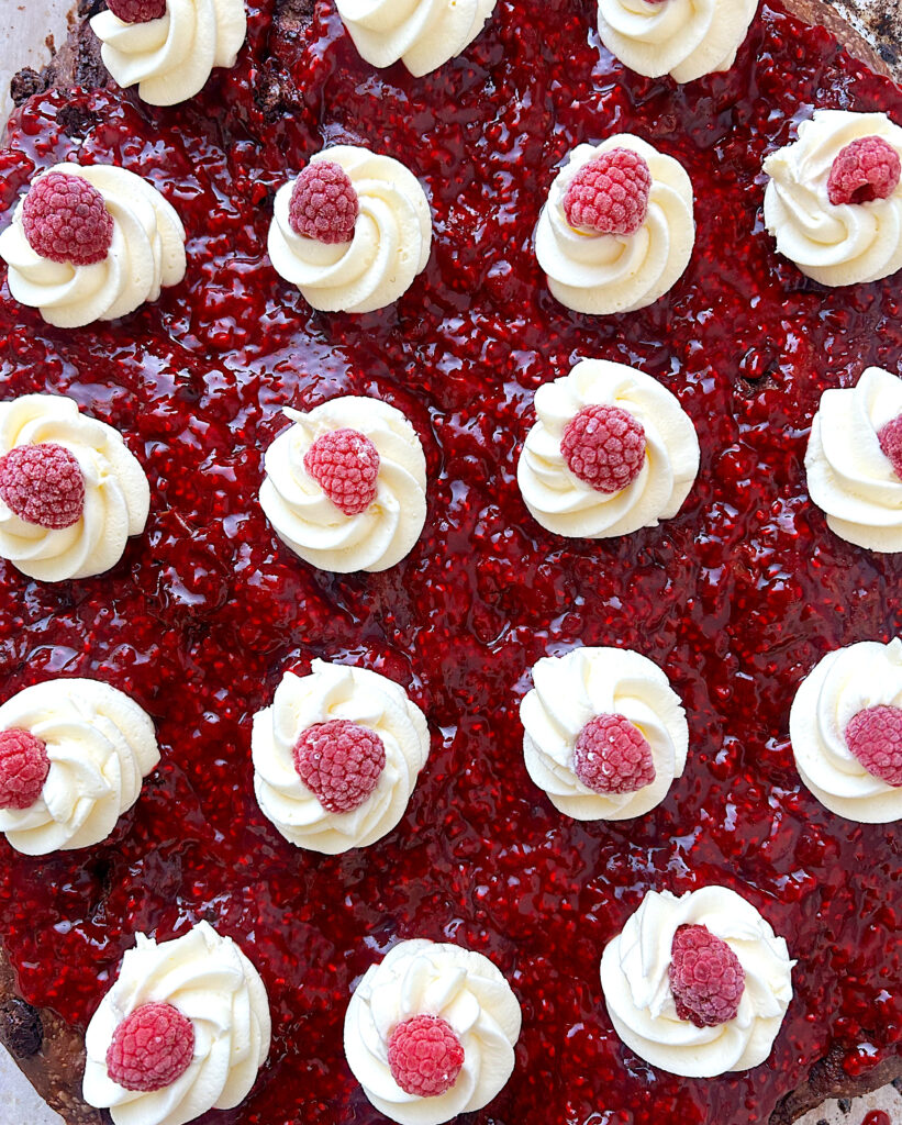 bread with raspberry sauce on top and little whipped cream swirls