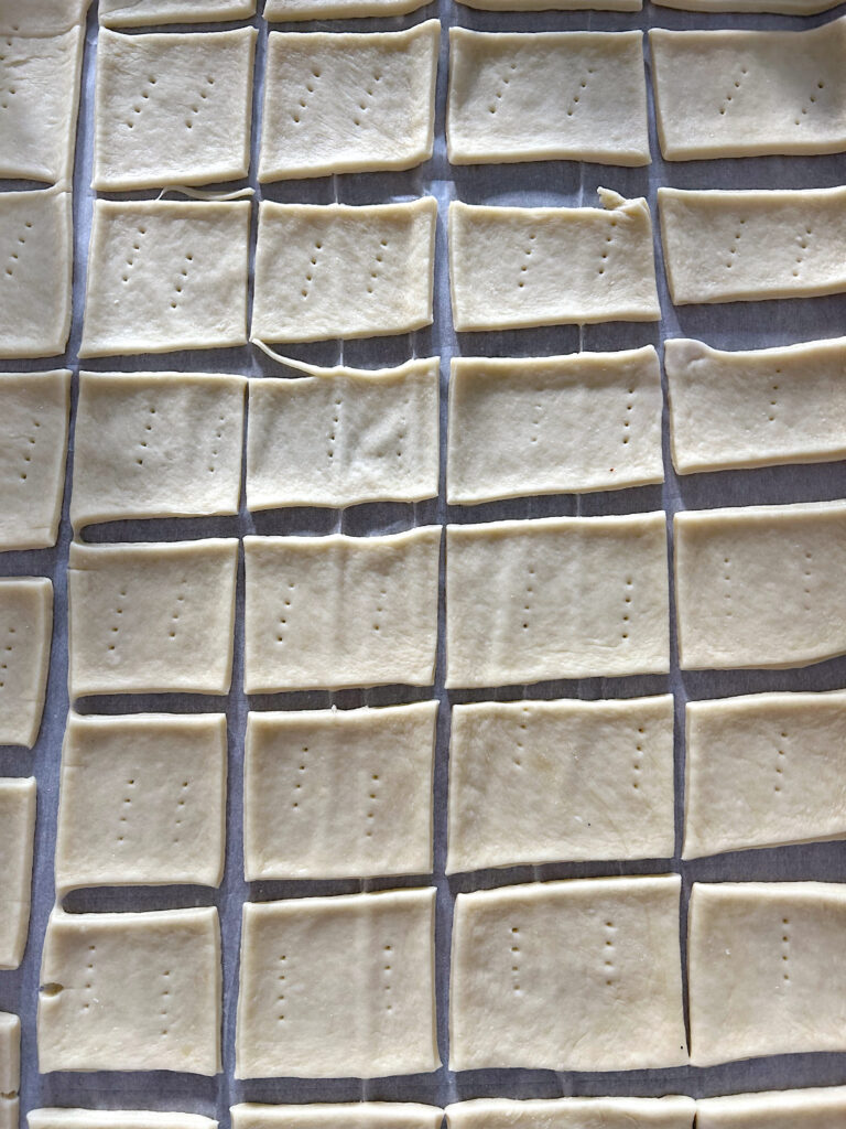 unbaked square crackers on a baking sheet