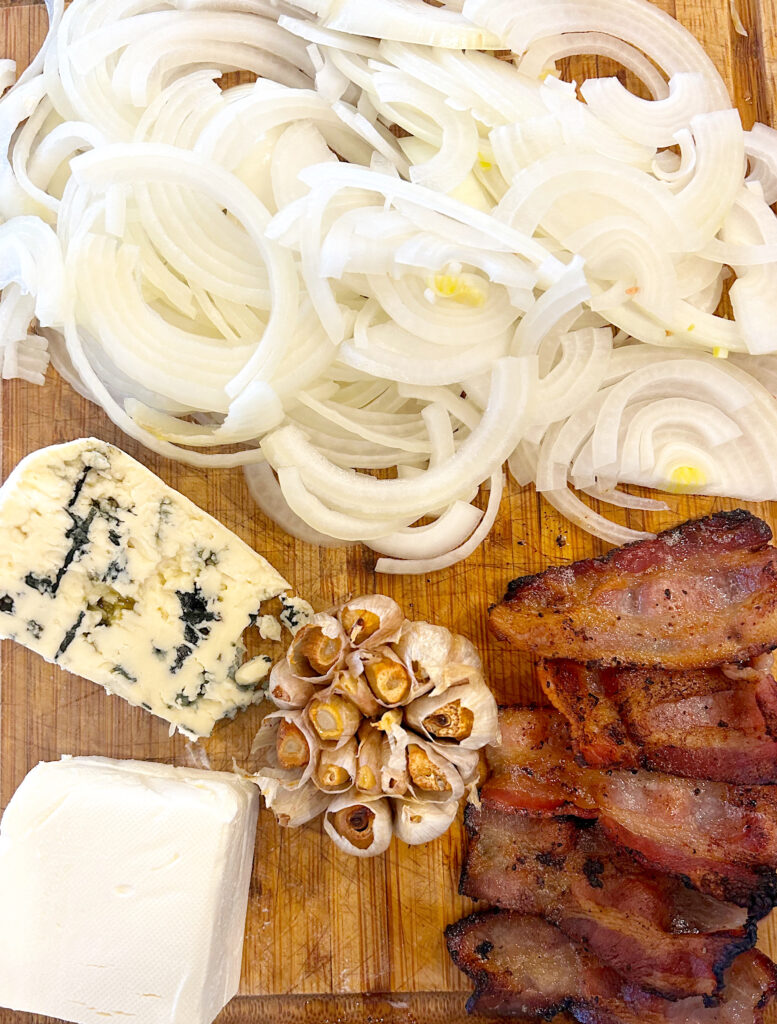 bacon, onions, garlic and blue cheese on a wood board
