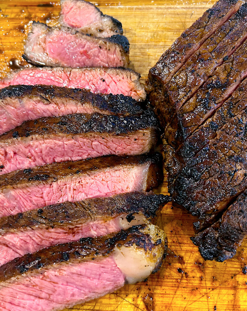 medium rare steak sliced on a wood board