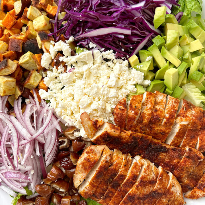 white bowl with lettuce, sweet potatoes, feta cheese, avocado and blackened chicken
