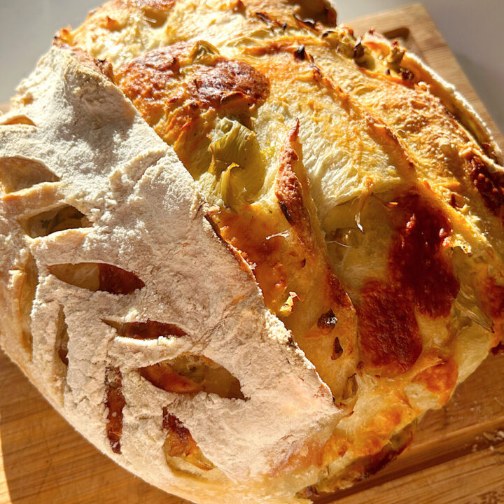 loaf of cheesy bread on a wood board