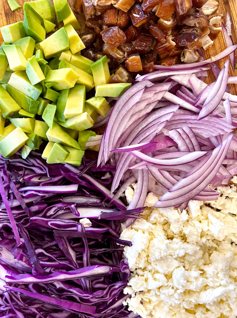 avocado, dates, cabbage, feta and red onion on a wood board