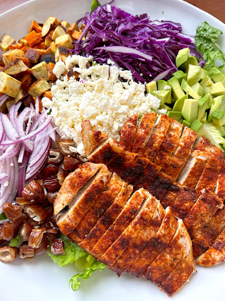 salad with blackened chicken, sweet potatoes, feta cheese and avocado