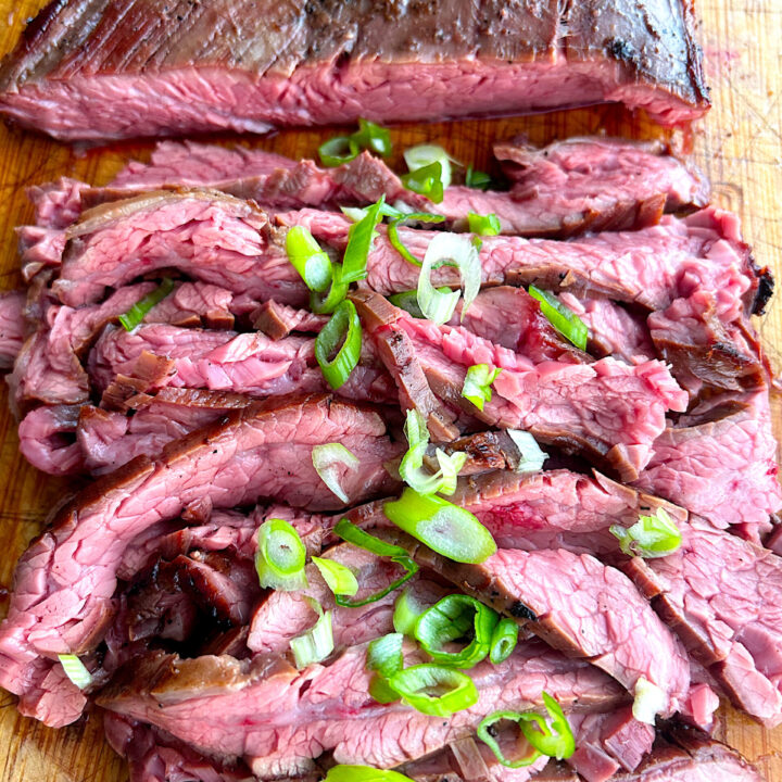 thinly sliced flank steak on a wood board