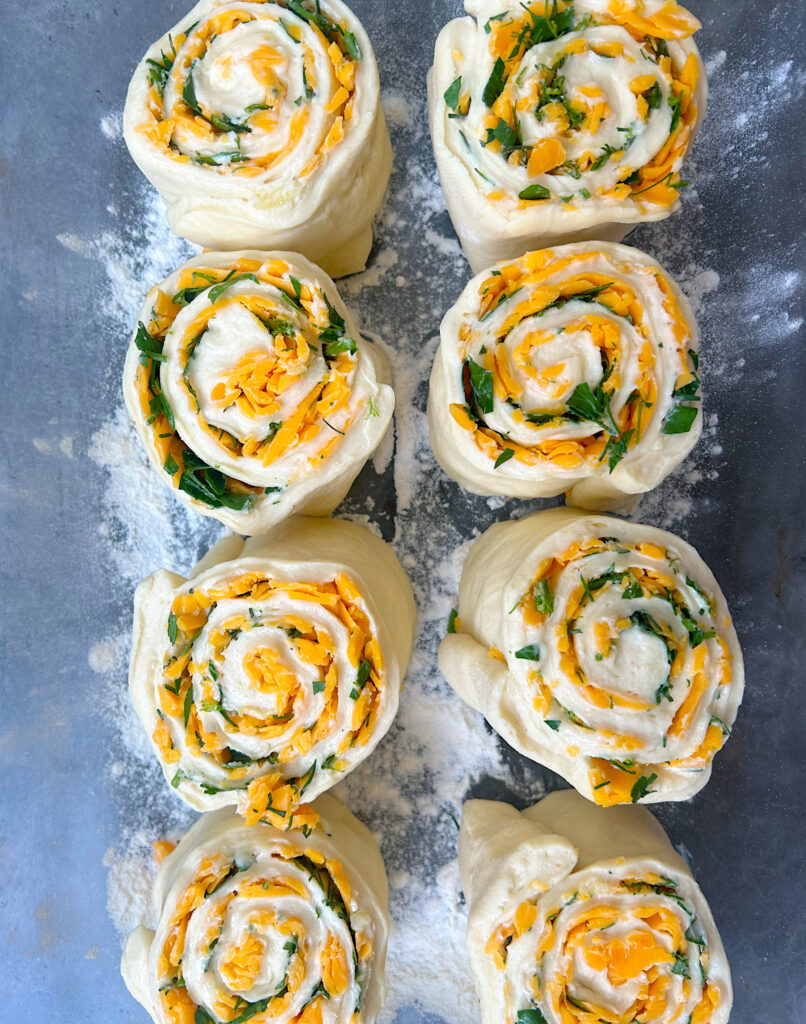 unbaked cheese and herb sourdough rolls in a baking dish 