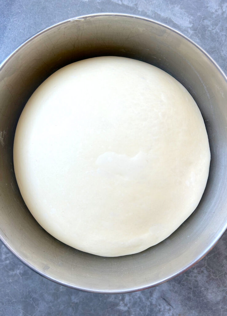 ball of proofed dough in a metal bowl 