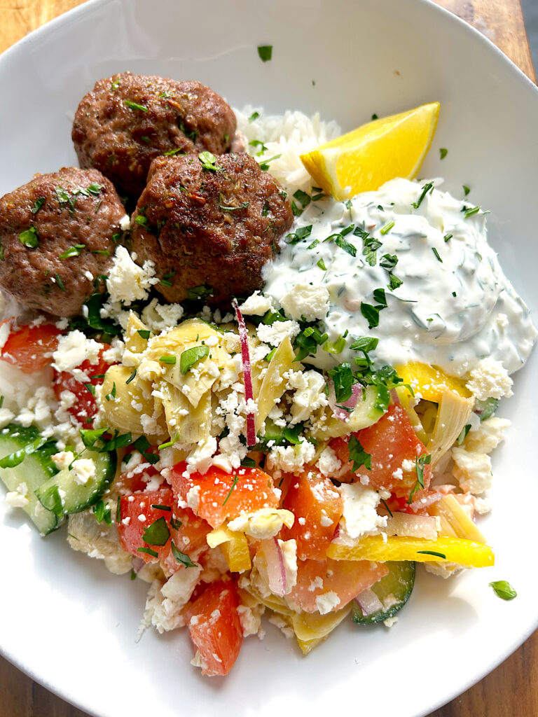 rice bowl with meatballs, greek salad and lemon dill sauce