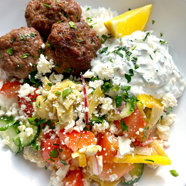 white bowl with rice, meatballs and greek salad