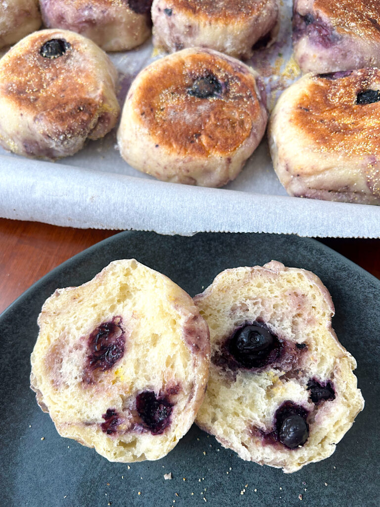 blueberry english muffin cut in half on a dark blue plate