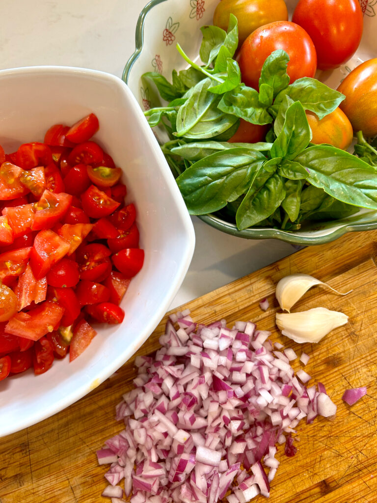 tomatoes, basil, red onion and garlic on a white counter