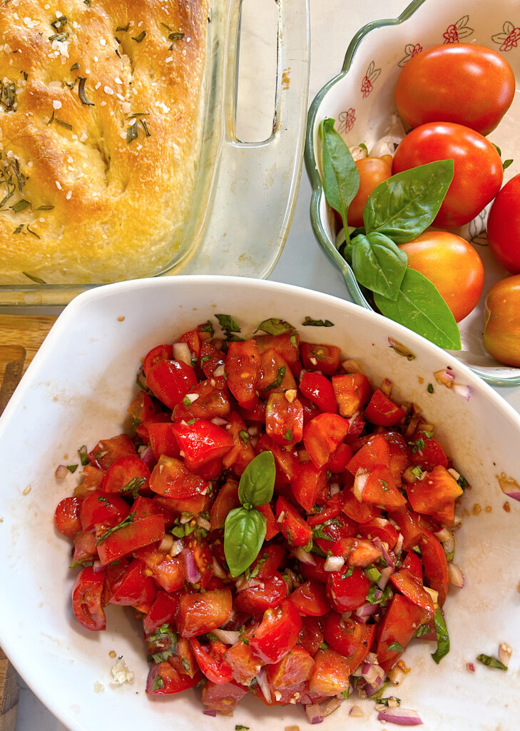 tomato bruschetta mizture in a white bowl with basil