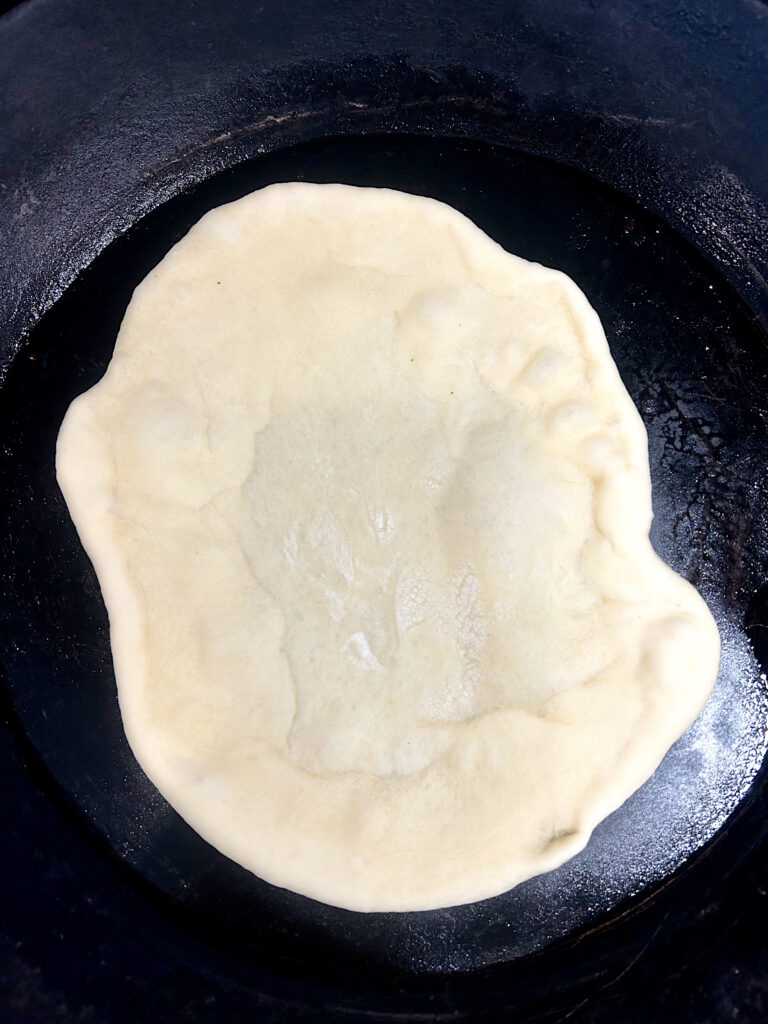 naan bread being cooked in a skillet