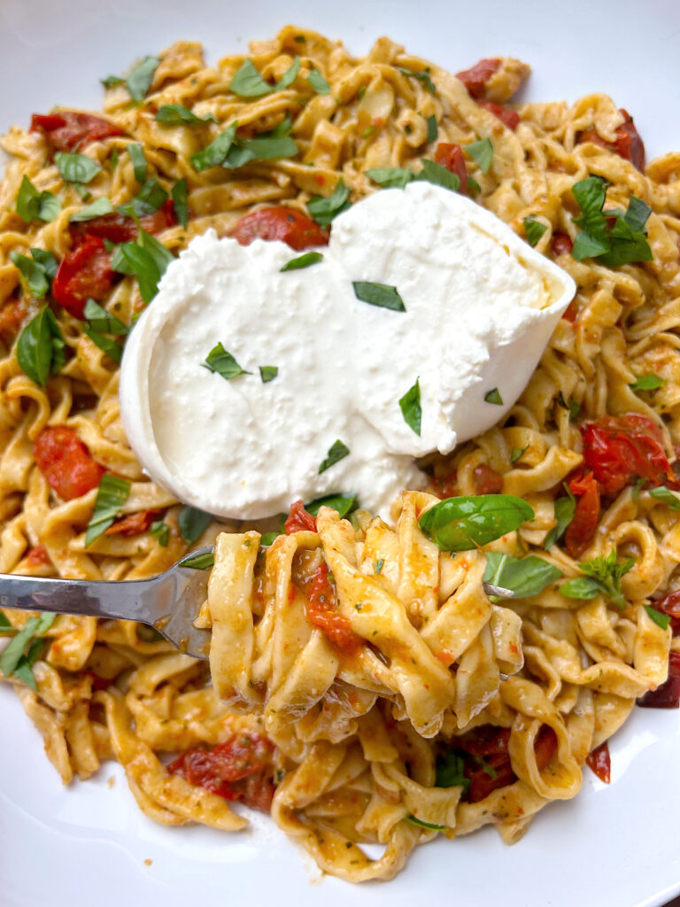 pesto and tomato psta with a ball of burrata cheese on top